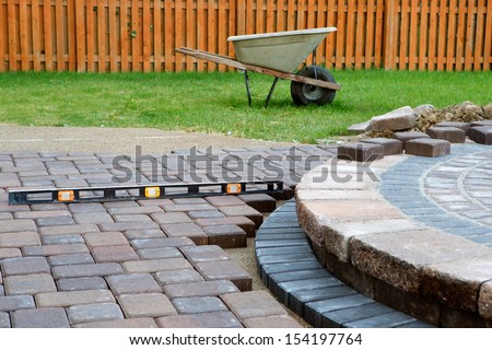 When building a patio prepare to use level and barrel constantly, patio island have polymeric sand laid and job completion almost done when final pavers cut and placed Royalty-Free Stock Photo #154197764