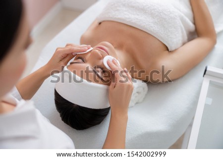 Cosmetologist wiping woman cheeks with soft sponges stock photo