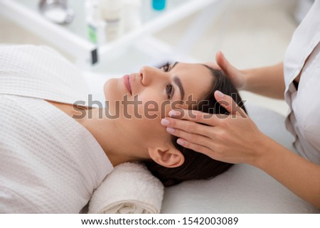 Close up of masseuse hands touching lady face stock photo