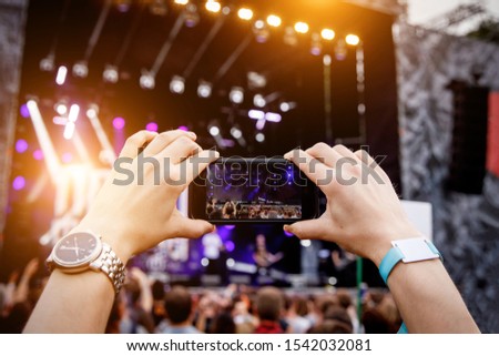 Recording concert by smartphone. Mobile phone in raised hands