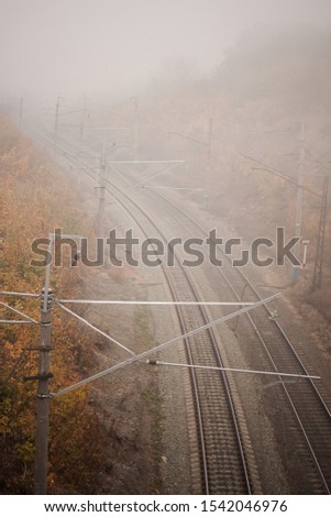 
railroad tracks in the afternoon in foggy autumn