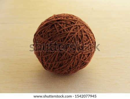 Round cotton brown thread on wood background