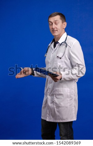 Male doctor in a white coat posing on a blue background