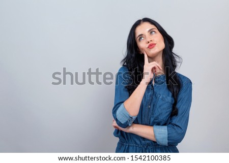 Young woman in a thoughtful pose on a gray background