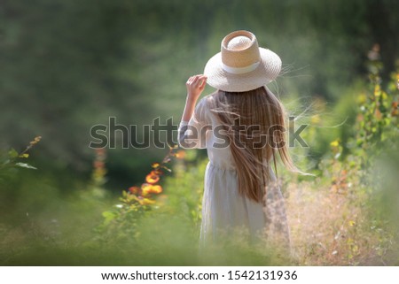 A young girl holds a hat with his hand. Photo without a face. Walk through the summer forest. Photo on nature. Copy space.