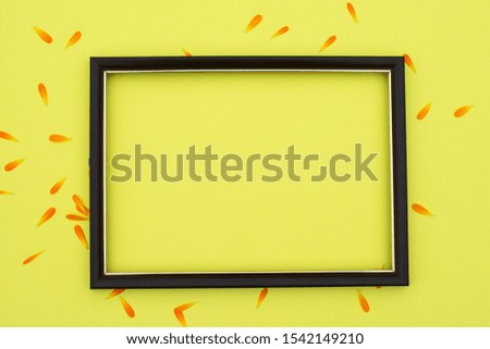 Photo frame on a yellow background with orange flower petals. Free space for an inscription.