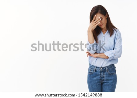 Embarrassed annoyed adult woman hiding face bend head down, facepalm, smirk irritated, not looking friend acting weird, feel humiliated uncomfortable, standing white background Royalty-Free Stock Photo #1542149888