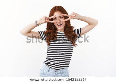 Sassy good-looking european redhead girl in striped summer t-shirt having fun, fool around show peace, victory signs over eyes, smiling amused open mouth excited, posing for holiday photo