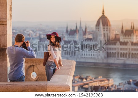 Young couple take pictures of each other on the view point from Fisherman Bastion in Budapest on sunrise.