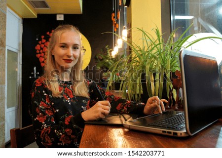 
Smiling woman working on a portable PC while sitting in a co-working