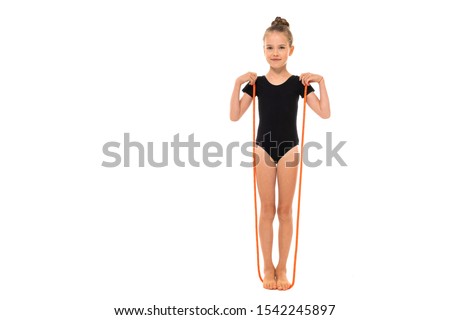 Picture of girl gymnast in black trico in full height stands on a jumping-rope isolated on a white background
