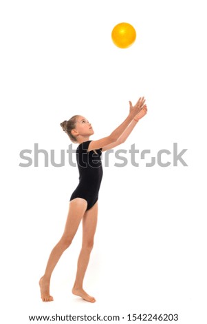 Picture of a gymnast girl in black trico full height throws the yellow ball up isolated on a white background