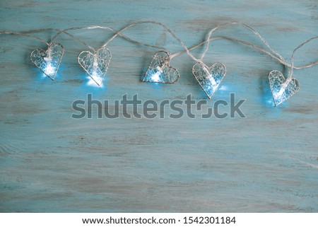 Light bulb on wooden background.  Space for your task or message. Glowing Christmas garland frame on blue wooden background. Closeup 