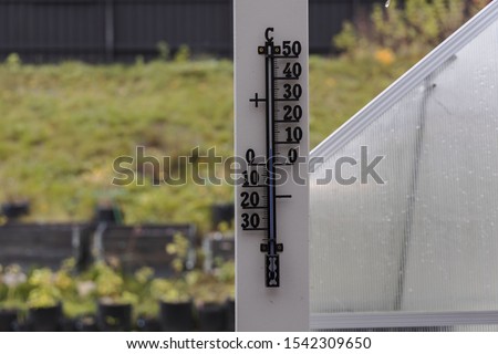 Close up view of outdoor thermometer on white wooden pillar. Beautiful autumn day backgrounds.
