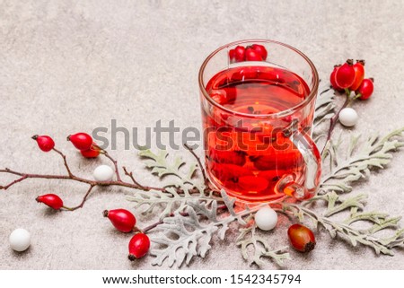 Hot dog-rose tea. Winter drink for good mood with fresh berries, leaves and candies. Stone concrete background, copy space, close up
