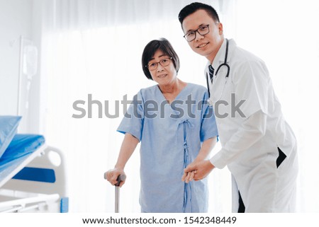 Asian man doctor help and support senior woman patient walking with a cane in hospital