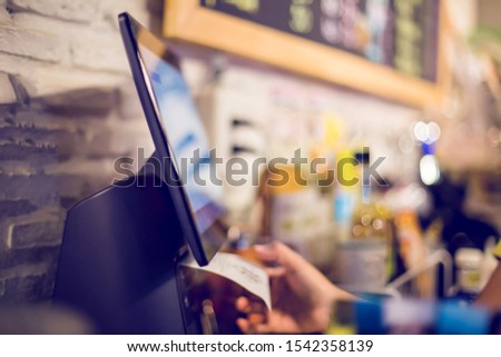 Blurry picture of cashier is printing receipt with cash register machine in cafe or store. Saleswoman receiving payment from customer in cafe or store. Blurry image for business background. Royalty-Free Stock Photo #1542358139