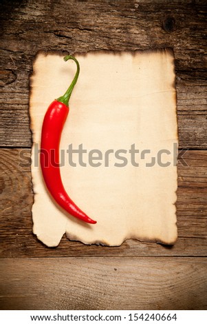 One Red Hot Chili Pepper with the Old Paper sheet on old wooden table