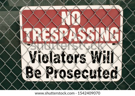 No trespassing signboard covered by metal grid on the street wall and on the darck background.Urban life, textured background.