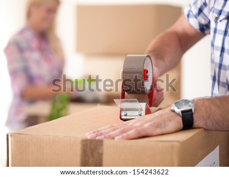 Close up of male hand packing cardboard box, concept moving house Royalty-Free Stock Photo #154243622