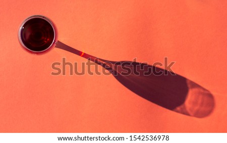glass of red wine with a shade on a coral color background top view flat lay, minimal art