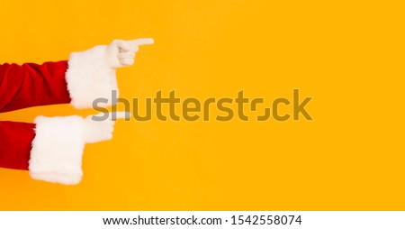 Santa Claus hands showing on copy space for promo or greetings on orange background, panorama