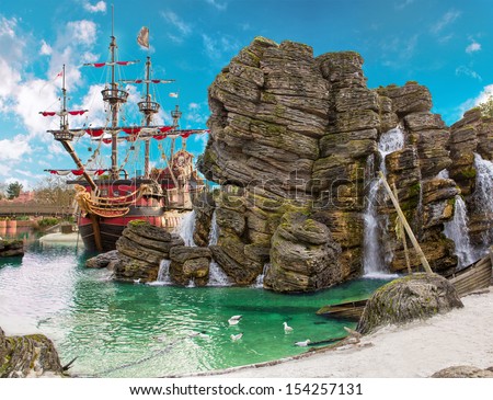 Pirate ship in the backwater of tropical pirate island, with big rock in form of skull near it