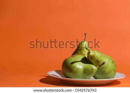 plate with three conference pears placed on a strong orange background