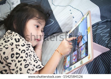 Cute Asian girl  watching kid program from tablet