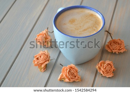 Coffee cup and dry roses in cremy color on blue vintage table, provence style
