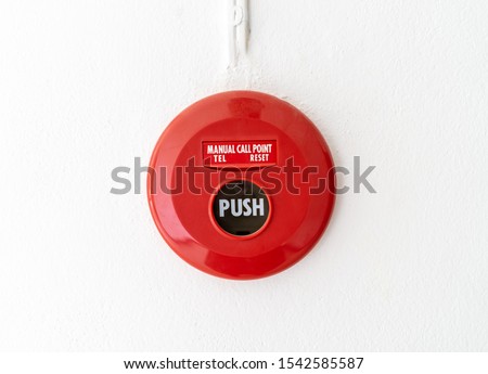 Red fire alarm mounted on cement wall for emergency alarm in the office building.