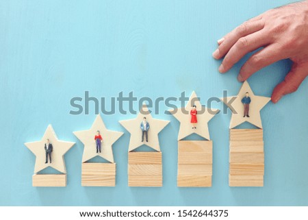 photo of 5 star symbols with people figures over wooden table ,human resources and management concept