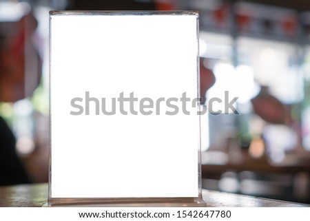 Blank mock up or label menu frame advertising in restaurant, Stand for booklets white paper sheets acrylic tent card on glass table in cafeteria, blurred background layout insert text for customer