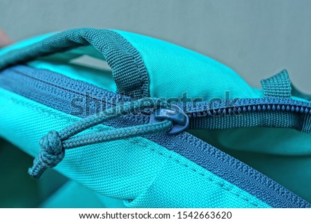 green zip and closure on the fabric of an open backpack