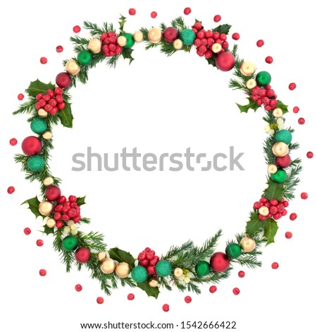 Christmas wreath abstract decoration with winter flora, baubles and loose holly berries on white background with copy space. Decorative symbol for the festive season.