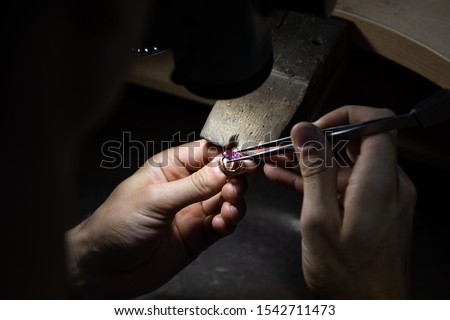 master of jewelry manually inserts gems into the frame of future jewelry. Working desk for craft jewelery making with professional tools. Sapphire diamond ring on the jeweler's desktop Royalty-Free Stock Photo #1542711473