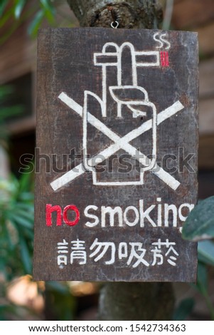 NO Smoking sign in old wood on the tree at garden