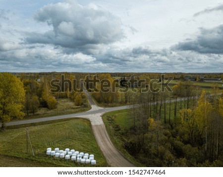 countryside view from above in Latvia with cultivated fields and road network in autumn  under dramatic sky