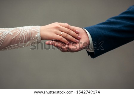 Close-up caressing hands of newlyweds. Gentle touch of hands of loving couple of newlyweds. Beautiful and romantic holding hands with woman`s hand on top of man`s hand with wedding rings on close up Royalty-Free Stock Photo #1542749174