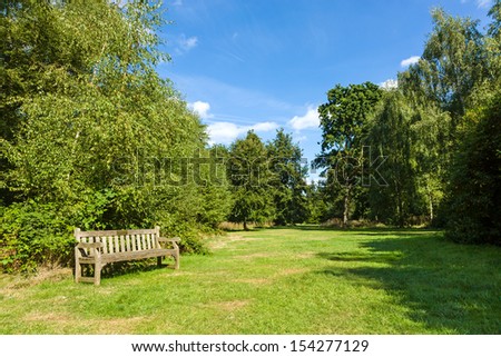 Park Bench in Beautiful Sunny and Shady Lush Green Garden Royalty-Free Stock Photo #154277129