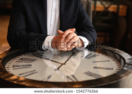 Time to business. Man put hands on table with clock. Deadline