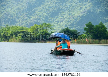 tourist sitting on boat for travel around Trang An, beautiful nature river and mountain, Trang An, Ninh Binh, Vietnam. subject is blurred.
