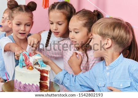 little cute children eating cake with fingers. close up photo. isolated pink background, studio shot