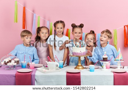 little adorable hungry children going to taste dessert, isolated pink background, studio shot