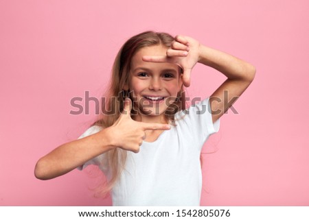 little beautiful happy girl making frame with hands and fingers Creativity and photography concept.lifestyle, body language, kid pretending a photographer. close up portrait, isolted pink background
