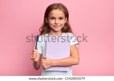 girl holding a book , pen. Back to school concept.isolated pink background, studio shot. lifestyle, free time, kid is ready to study. Royalty-Free Stock Photo #1542805079