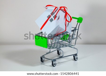 House with a gift ribbon in a shopping cart. Real estate sale.Concept: buying, selling and renting real estate.