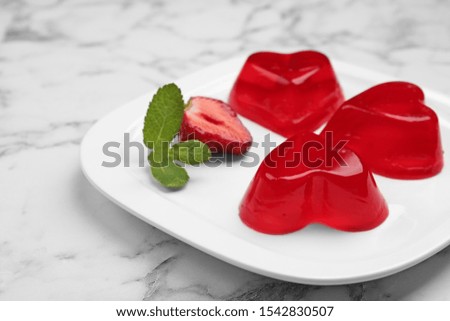 Plate of tasty strawberry jelly on marble table, space for text