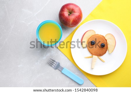 Tasty pancake served with apple and juice on marble table, flat lay. Creative idea for kids breakfast