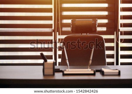 Business office workplace. Sunlight at work place for chief, boss or other employees. Table and comfortable chair. Light through the half open blinds